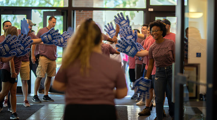 students waving high-five foam hands